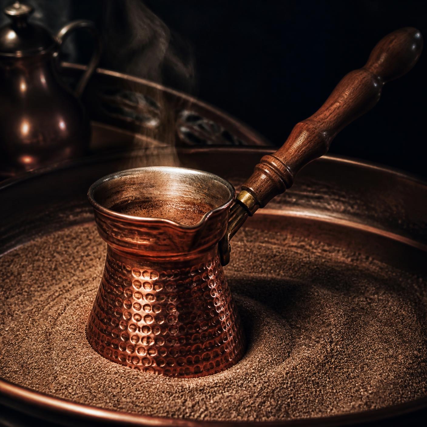Copper Turkish cezve brewing coffee over hot sand